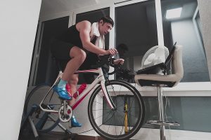 Man cycling on the machine trainer he is exercising in the home at night. 